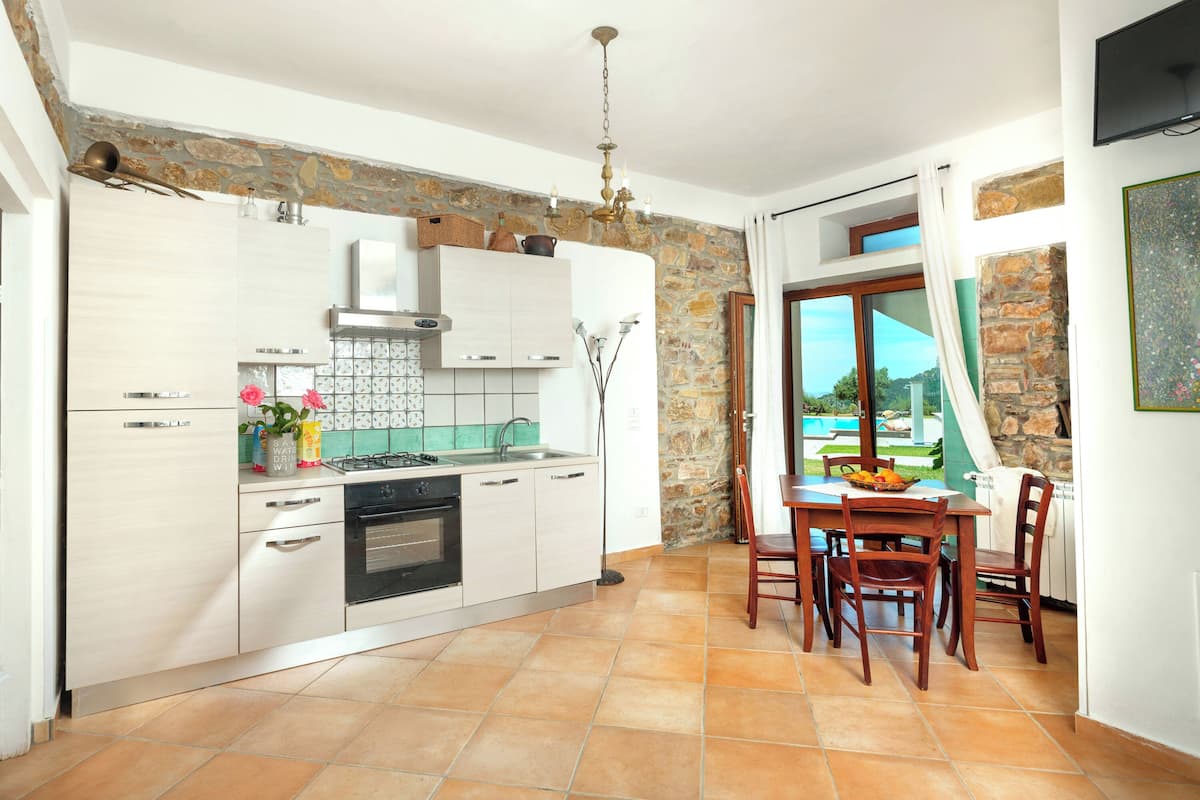 A modern kitchen with white cabinets, a gas stove, and a dining area with a table and chairs.