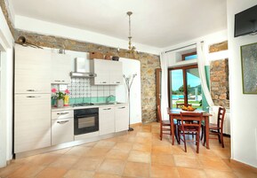 Una cocina moderna con armarios blancos, una estufa a gas y un comedor con mesa y sillas.