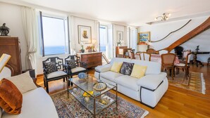 Un salón amplio con un sofá blanco, una mesa de centro de cristal, y un comedor con sillas y mesa de madera.