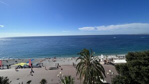 Una playa con cielo despejado, una zona de arena con sombrillas y algunas personas.
