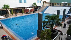 Piscina com água azul cristalina, rodeada por espreguiçadeiras e palmeiras.