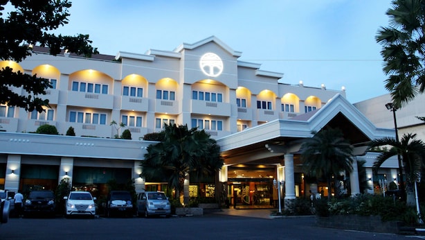 Hotel com grande placa, várias varandas e estacionamento.