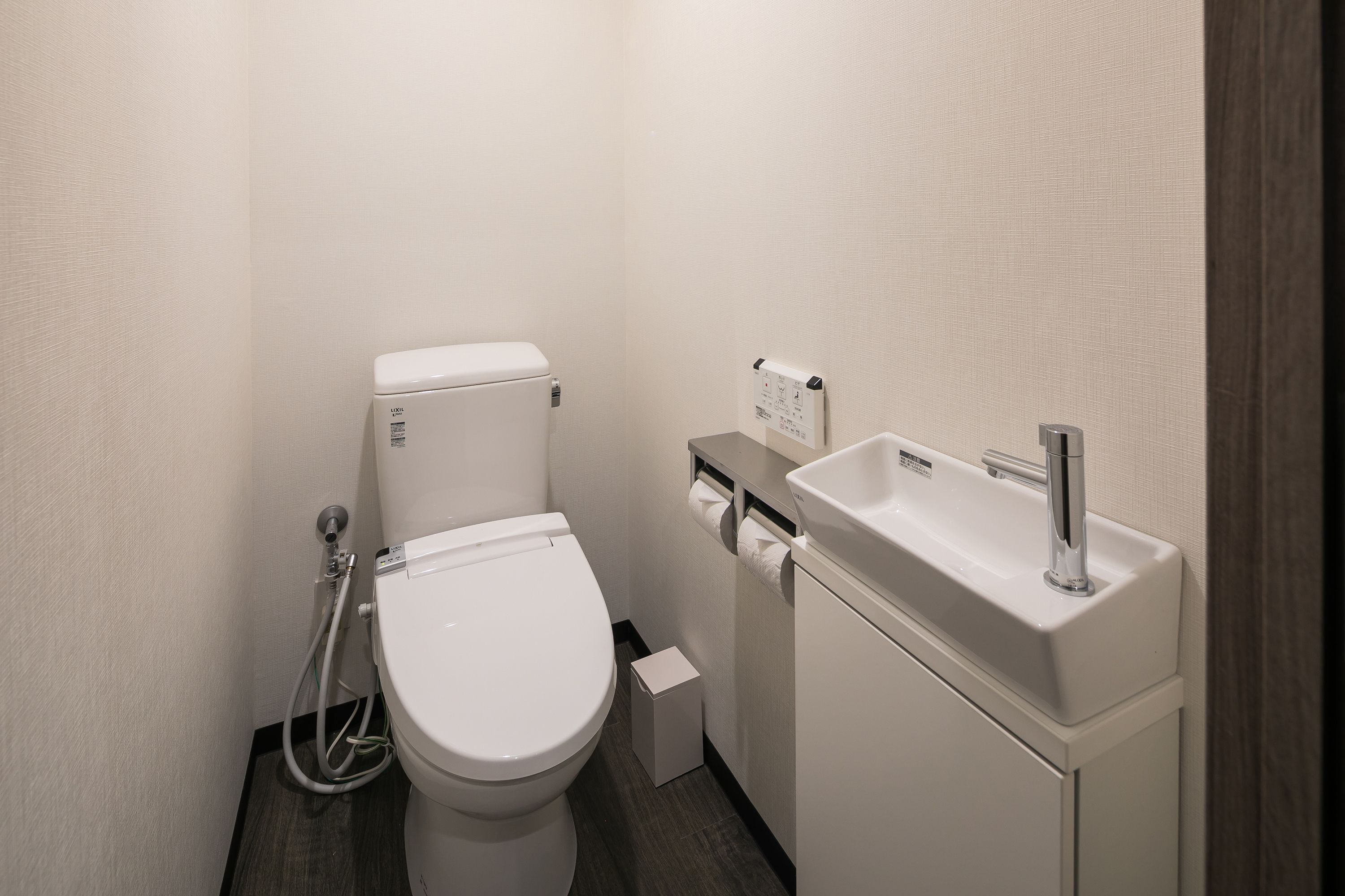 A small, modern bathroom with a toilet, a sink, and a shower.