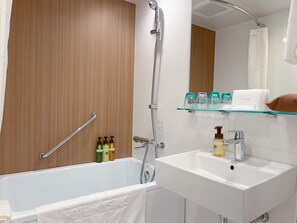 A modern bathroom with a bathtub, a shower, a sink, and a glass shelf with toiletries. - Hotel Mystays Nagoya Nishiki (Nagoya)