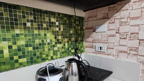 A kitchen with a green mosaic backsplash, a white countertop, and a brick-patterned wall. - 1 Bedroom Condo at One Oasis Condominuim (Cagayan de Oro)