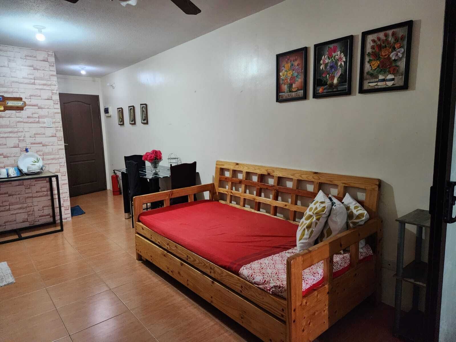 Una stanza con un letto di legno, un tavolino con sedie, una parete con decorazione a mattoni e tre quadri appesi al muro.