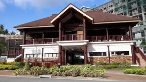 A two-story building with a brown roof, a balcony on the upper floor, and a stone facade. - 1 Bedroom Condo at One Oasis Condominuim (Cagayan de Oro)
