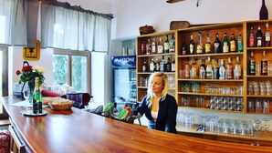 A bar area with a wooden counter, shelves of liquor bottles, and a ceiling fan. - Hotel Pod Šikmou Věží (Holín)