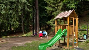 A playground with a wooden playhouse and a green slide. - Hotel Pod Šikmou Věží (Holín)