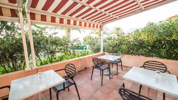 Una terrazza esterna con tavoli e sedie, circondata dal verde e vista sul paesaggio.
