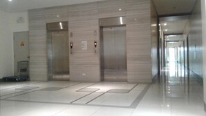 Un área de ascensores moderna con dos ascensores, una escalera de metal y un suelo pulido.