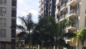 Un moderno edificio de apartamentos con un patio circular que presenta palmeras y una fuente central.