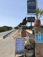 Señal de carretera para Hostal Restaurante El Mero, con servicios como mariscos frescos, piscina y Wi-Fi.