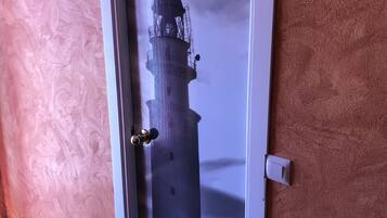 Une porte dotée d’un panneau de verre représentant la silhouette d’un phare.