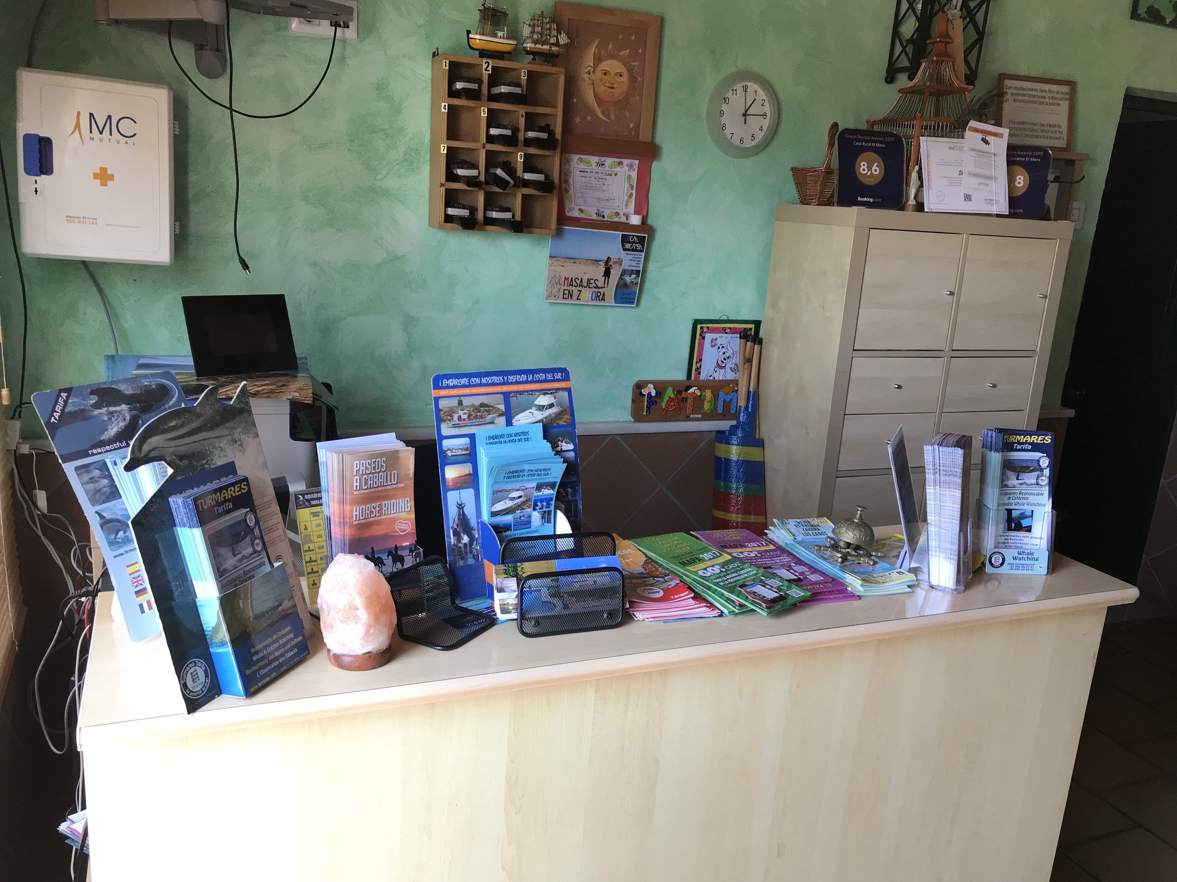 Una reception con brochure, una lampada di sale e un orologio a parete.