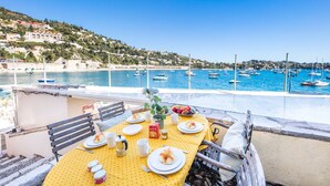 A table set for a meal with a view of a marina and boats. - QUAI DES MARINIERES AP2015 by RIVIERA HOLIDAY HOME (Villefranche-sur-Mer)