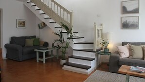 A living room with a staircase, a sofa, a coffee table, and a plant. - Spacious two bedroom house near the beach with private terrace and sea views (Puerto del Carmen)