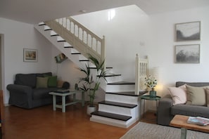 Un salon avec un escalier, un canapé, une table basse et une plante.