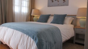 A neatly made bed with a blue blanket, two bedside lamps, and a painting of birds on the wall. - Spacious two bedroom house near the beach with private terrace and sea views (Puerto del Carmen)