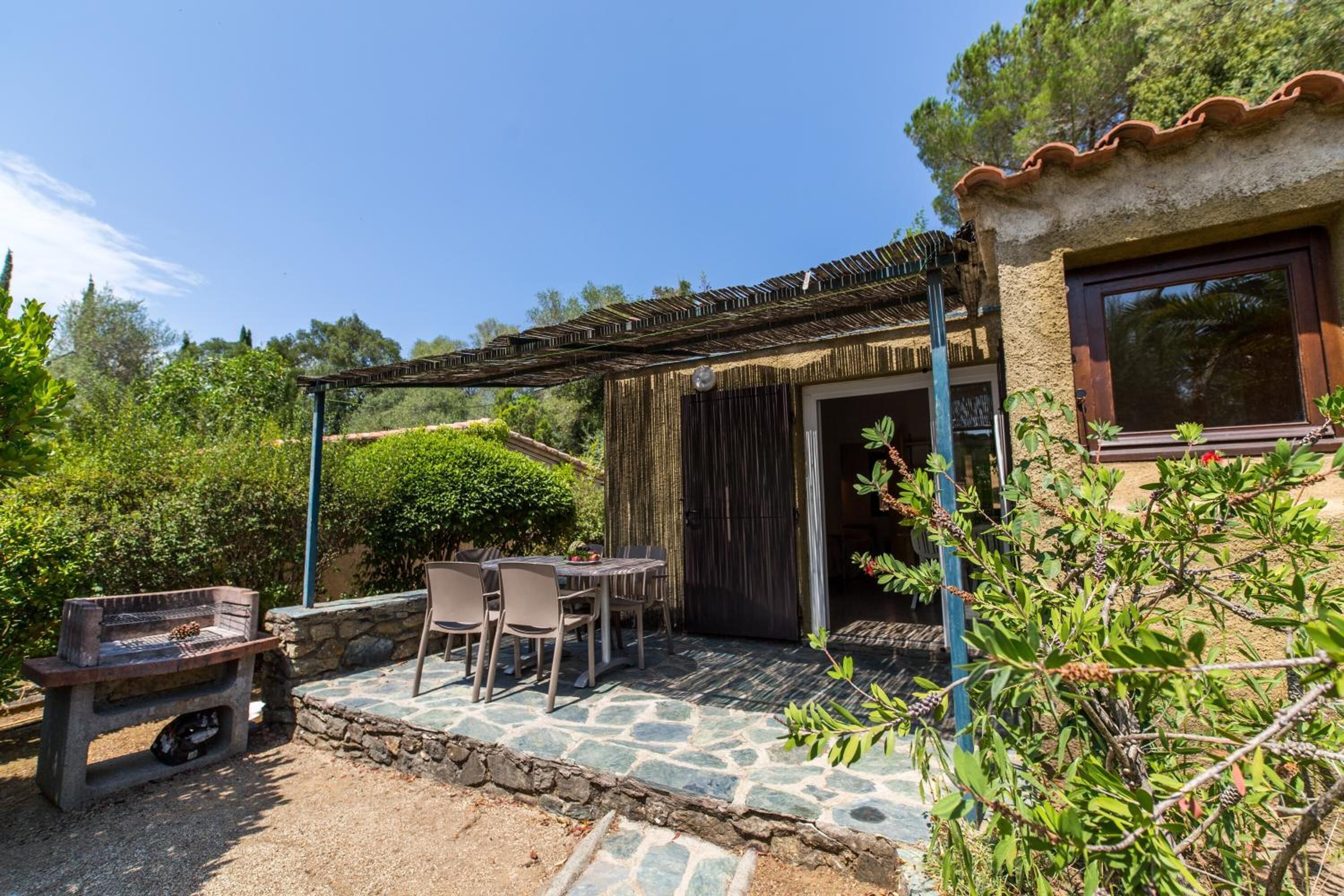 A patio with stone flooring, a grill, and a table with chairs.