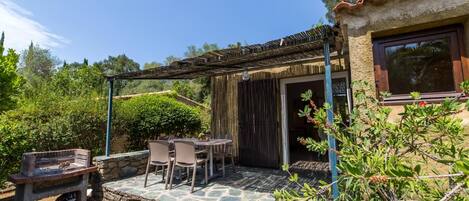 A patio with stone flooring, a grill, and a table with chairs.