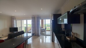 Eine moderne Küche mit Flachbildfernseher, ein Essbereich mit Tisch und Stühlen sowie ein Balkon mit Landschaftsblick.