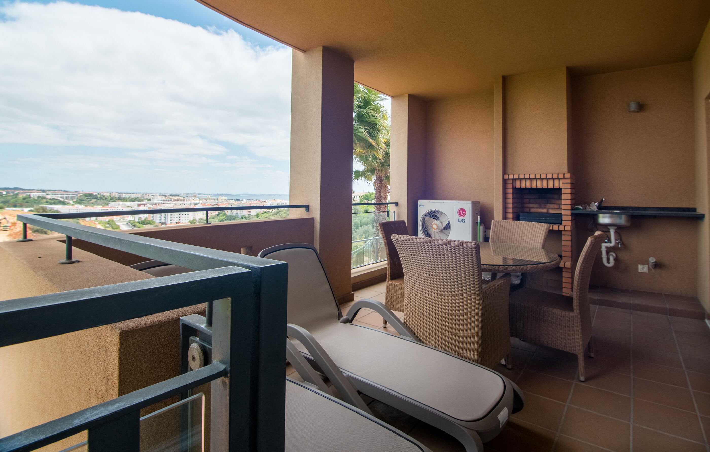 Un balcon avec vue sur la ville, une cheminée en briques et deux fauteuils confortables.