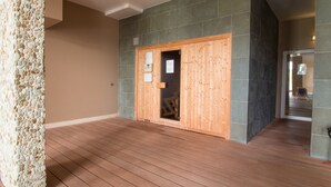 Ein Raum mit einer Holztür zur Sauna, einer Steinwand und einem Holzboden.