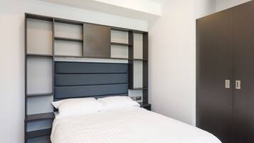 A modern bedroom with a bed, built-in shelving, and a wardrobe.