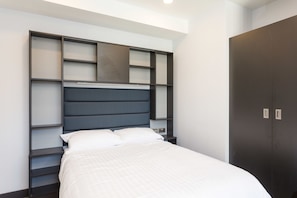 A modern bedroom with a bed, built-in shelving, and a wardrobe. - Destiny Student - New Mill (Dublin)