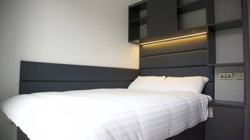 Une chambre à coucher moderne, avec un lit, des étagères intégrées et une table de chevet.