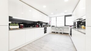 A modern kitchen with white cabinetry, a central island, and a large window providing natural light. - Destiny Student - New Mill (Dublin)