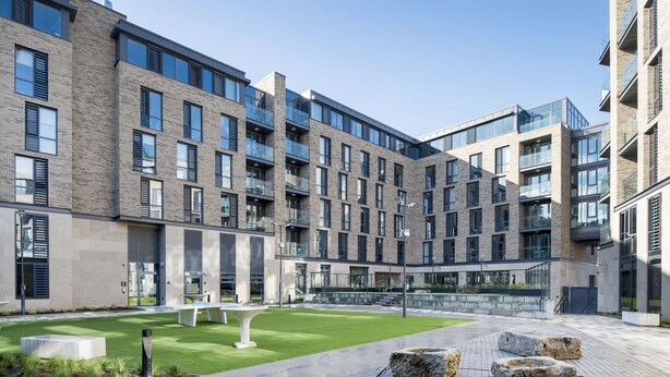 A modern building with multiple floors, large windows, and a courtyard with seating and greenery. - Destiny Student - New Mill (Dublin)