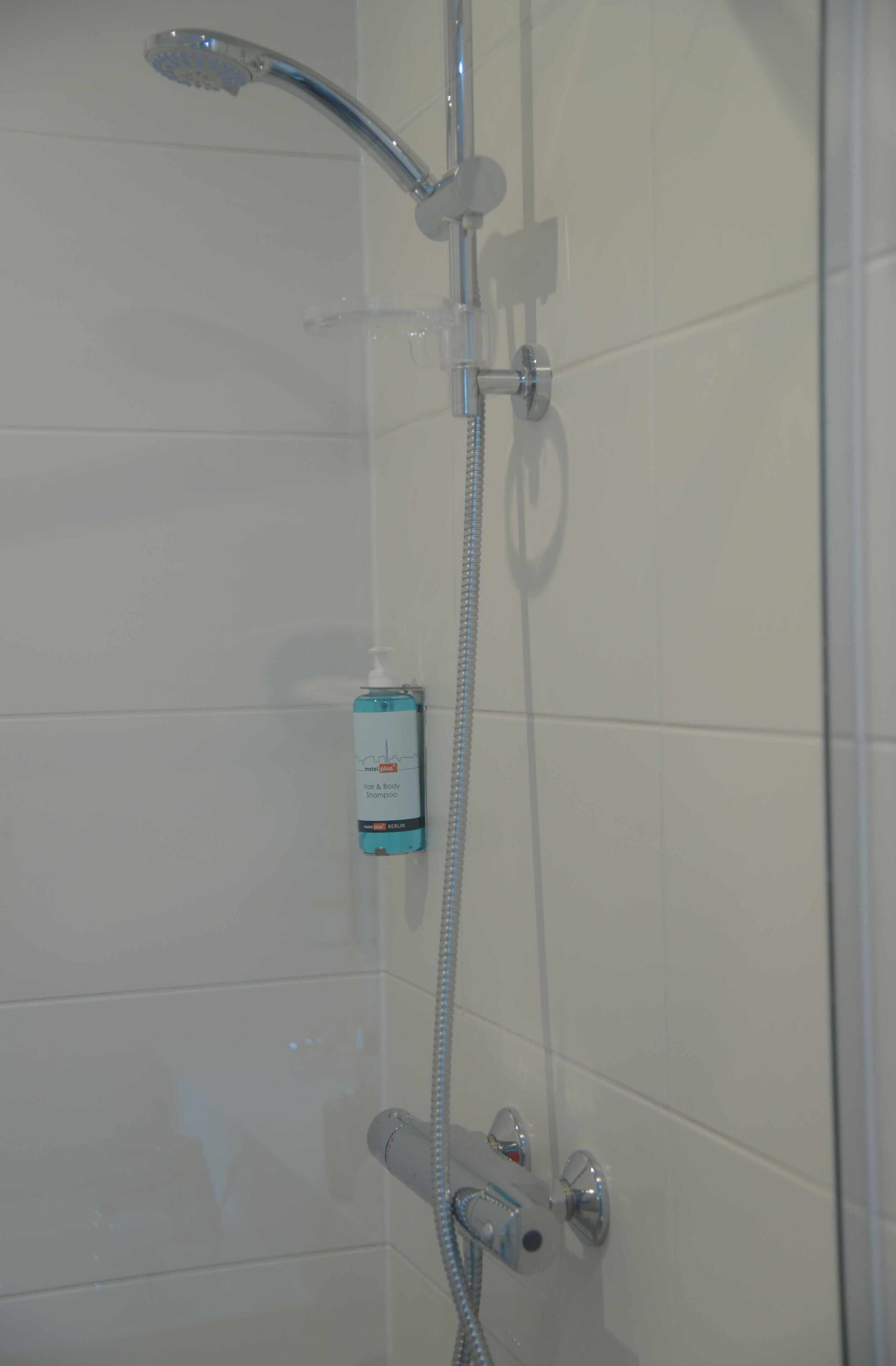 A shower with a handheld showerhead and a handheld shower attachment.