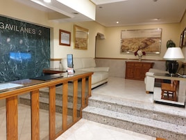 Un hall de hotel con un mostrador de recepción de mármol, un sofá, una mesa de centro, un armario de madera y una escalera con peldaños de granito.