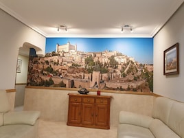 Una sala de estar con un gran mural de la ciudad, un armario de madera y dos sofás.