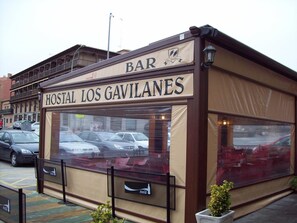 Un bar llamado 'Hostal Los Gavilanes' con un amplio escaparate y un cartel de Coca-Cola.