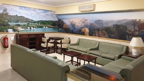 A hotel lobby with a large scenic mural, green seating, a fireplace, and a fire extinguisher. - Hostal Los Gavilanes 2 (Toledo)
