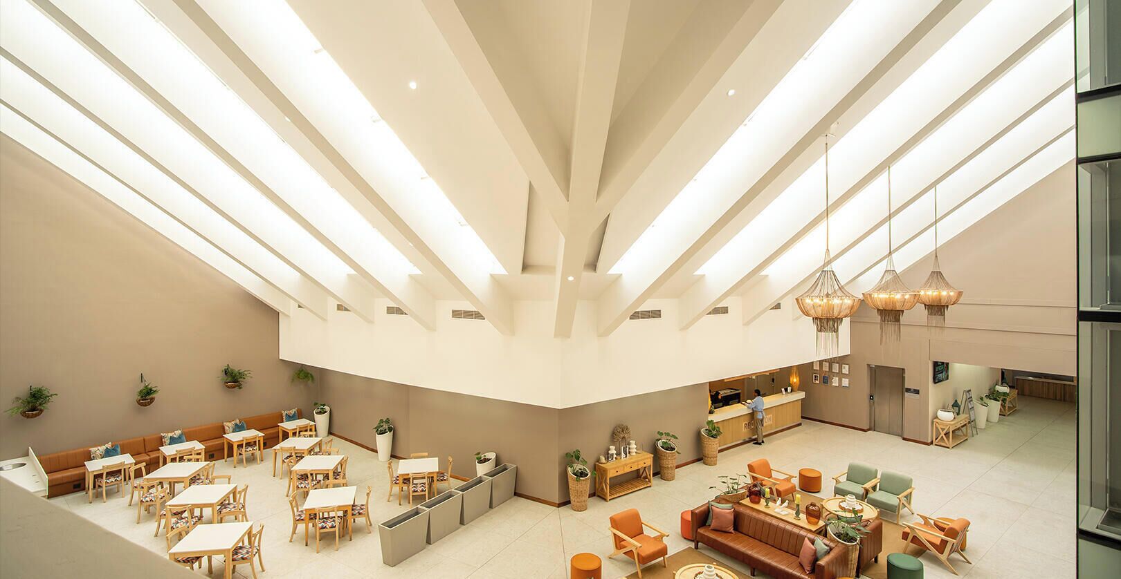 A spacious hotel lobby with a high ceiling, multiple seating areas, and a reception desk.