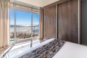 Een hotelkamer met een groot raam, een bed met een decoratieve spreidek en houten lambrisering.