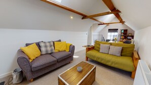 A loft-style living room with two sofas, a coffee table, and exposed wooden beams. - Beautiful Coach House (Gloucester)