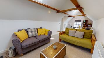A loft-style living room with two sofas, a coffee table, and exposed wooden beams.