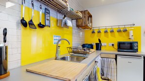 A kitchen with a yellow backsplash, stainless steel sink, and a microwave. - Beautiful Coach House (Gloucester)