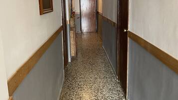 Un pasillo con suelo estampado, puertas de madera y cuadros en las paredes.