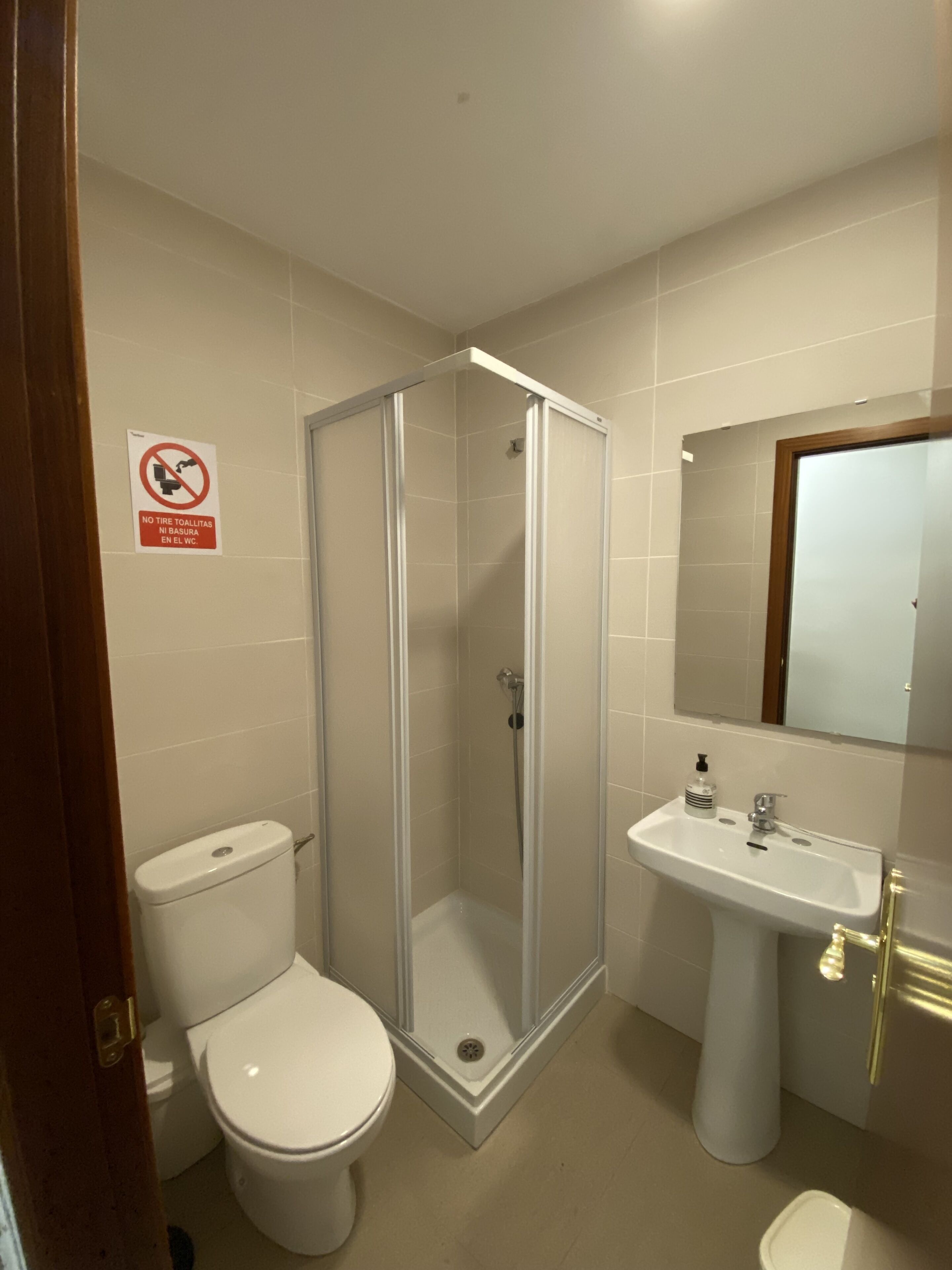 Un baño con inodoro, cabina de ducha y lavabo.