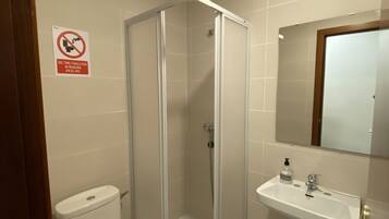 Un baño con inodoro, cabina de ducha y lavabo.