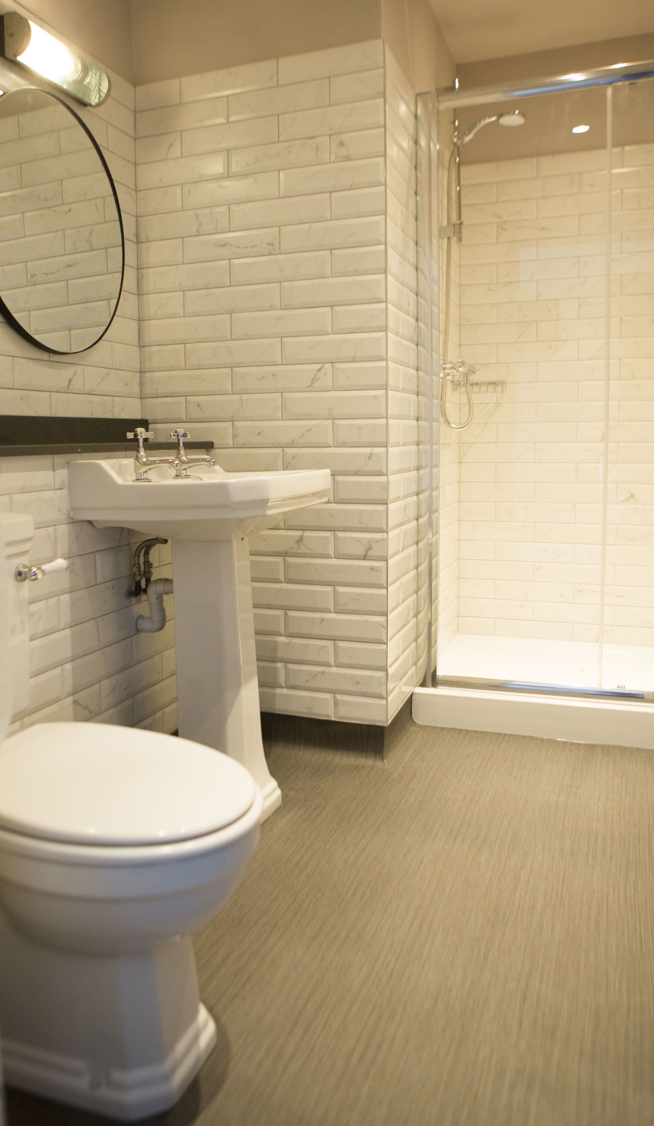 Et badeværelse med toilet, håndvask og bruser.