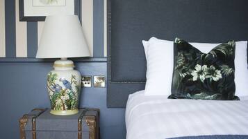 Un dormitorio ordenado con una cama, una mesita de noche con lámpara y una maleta.