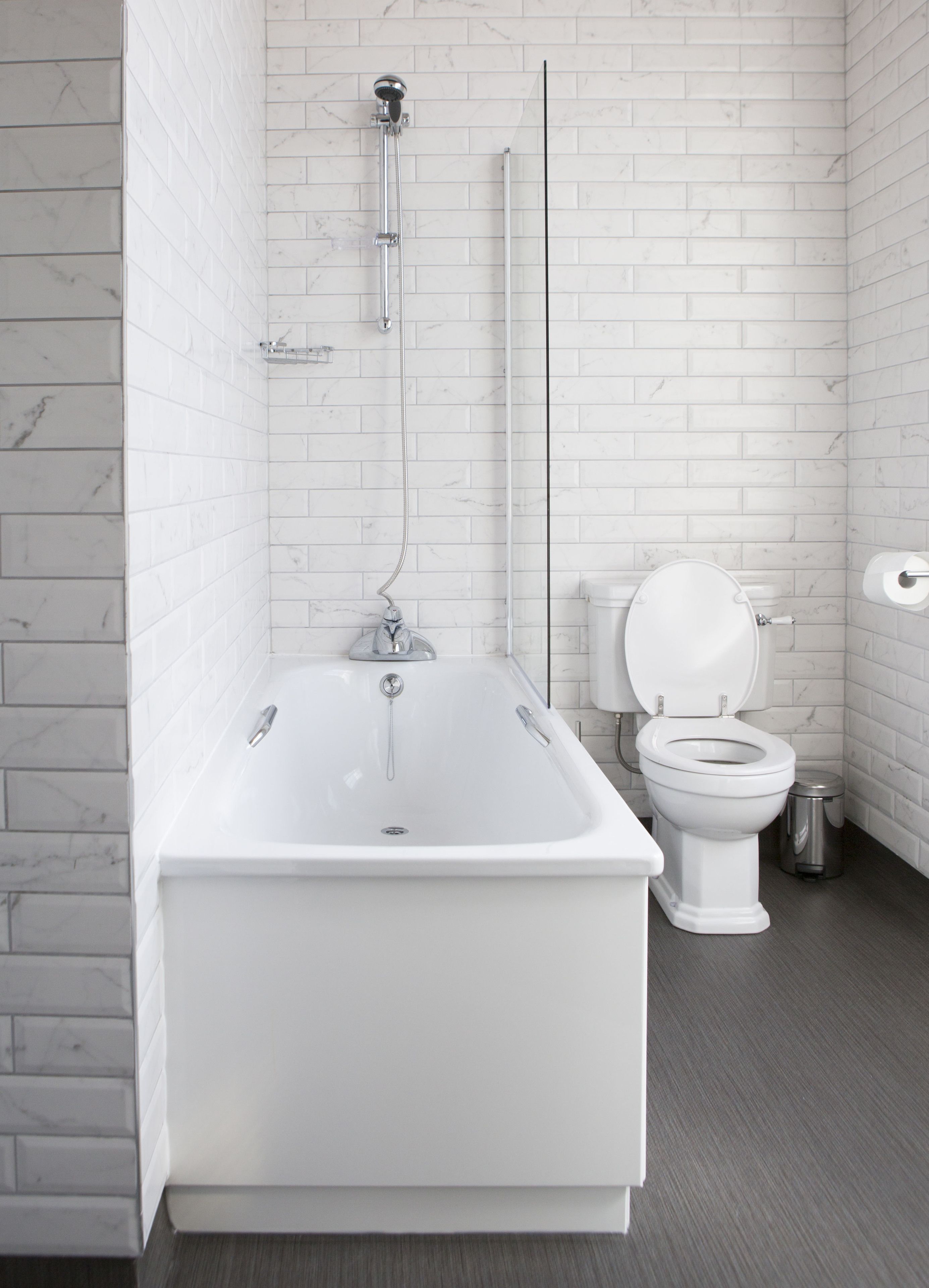 A modern bathroom with a freestanding bathtub, a toilet, and a showerhead.