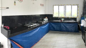 A kitchen with black countertops, a gas stove, a sink, and a window with a view of greenery. - Seabreeze Beach Lodge (Nasugbu)